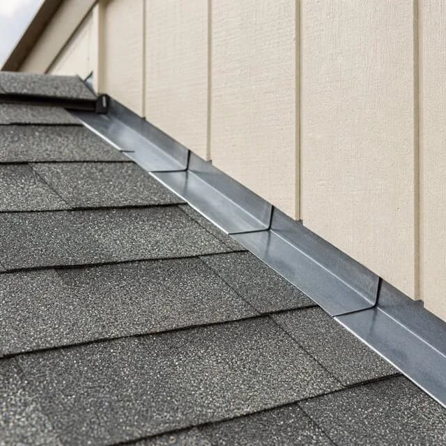 Metal flashing sealing the seam where a shingle roof meets a sided wall