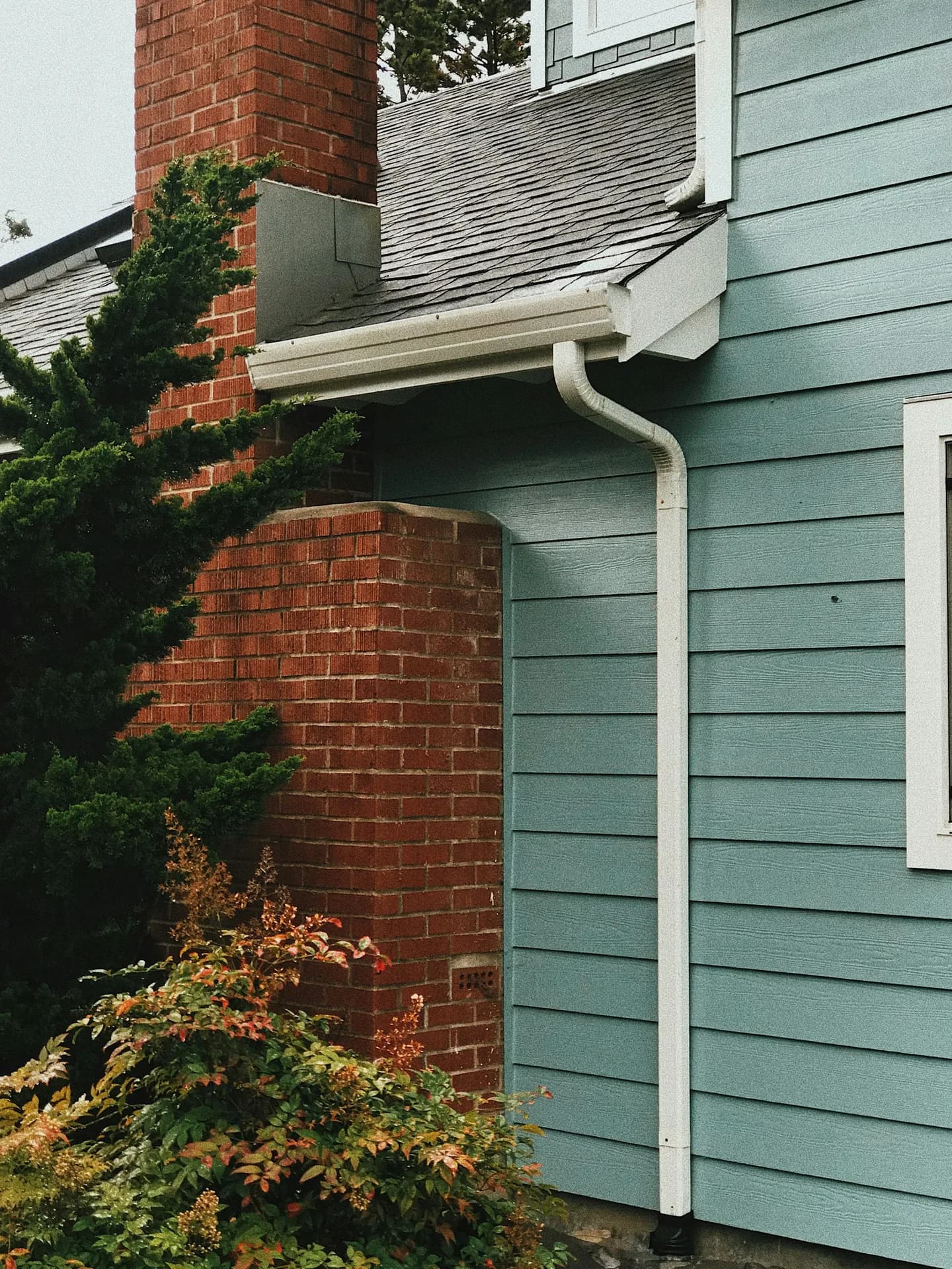 Seamless gutter and downspout on a blue-sided home
